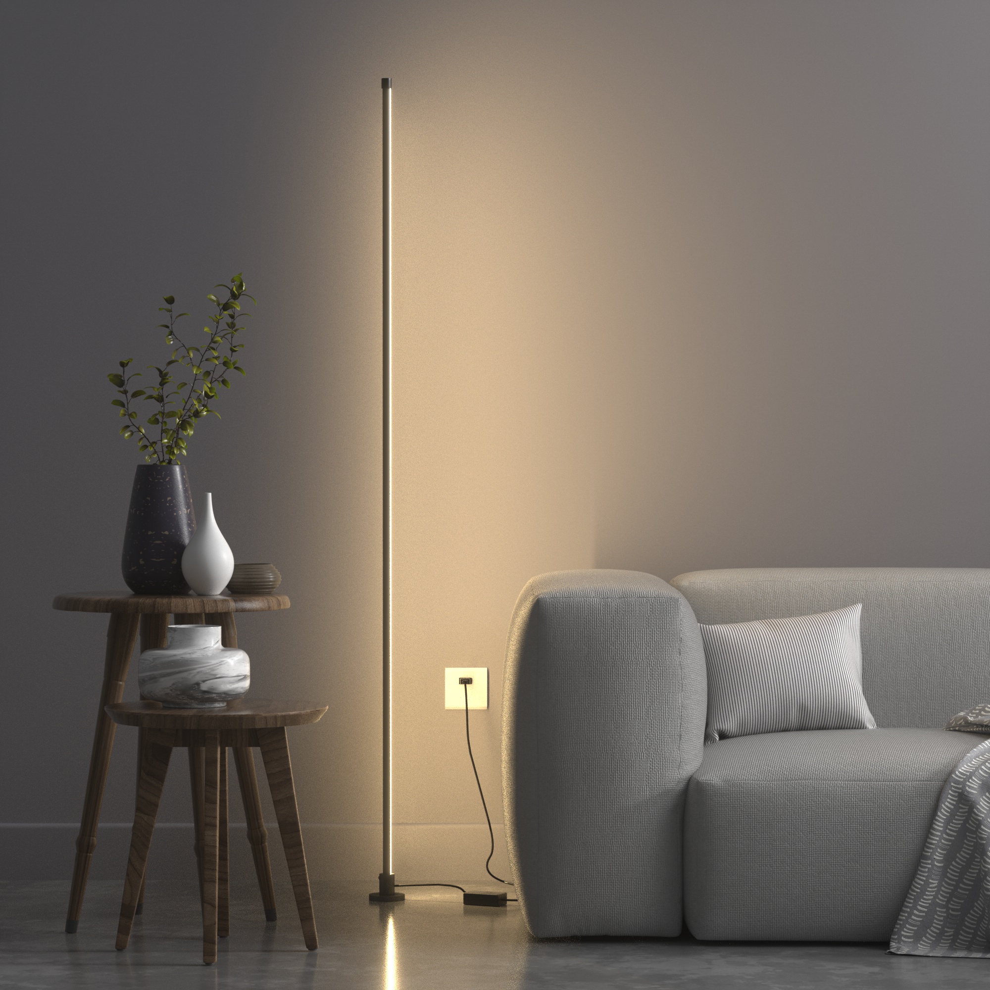 一支極簡設計的智慧落地氛圍燈，擺設在灰色沙發旁的角落，其光線投射於牆面，營造出溫暖且柔和的間接照明氛圍。