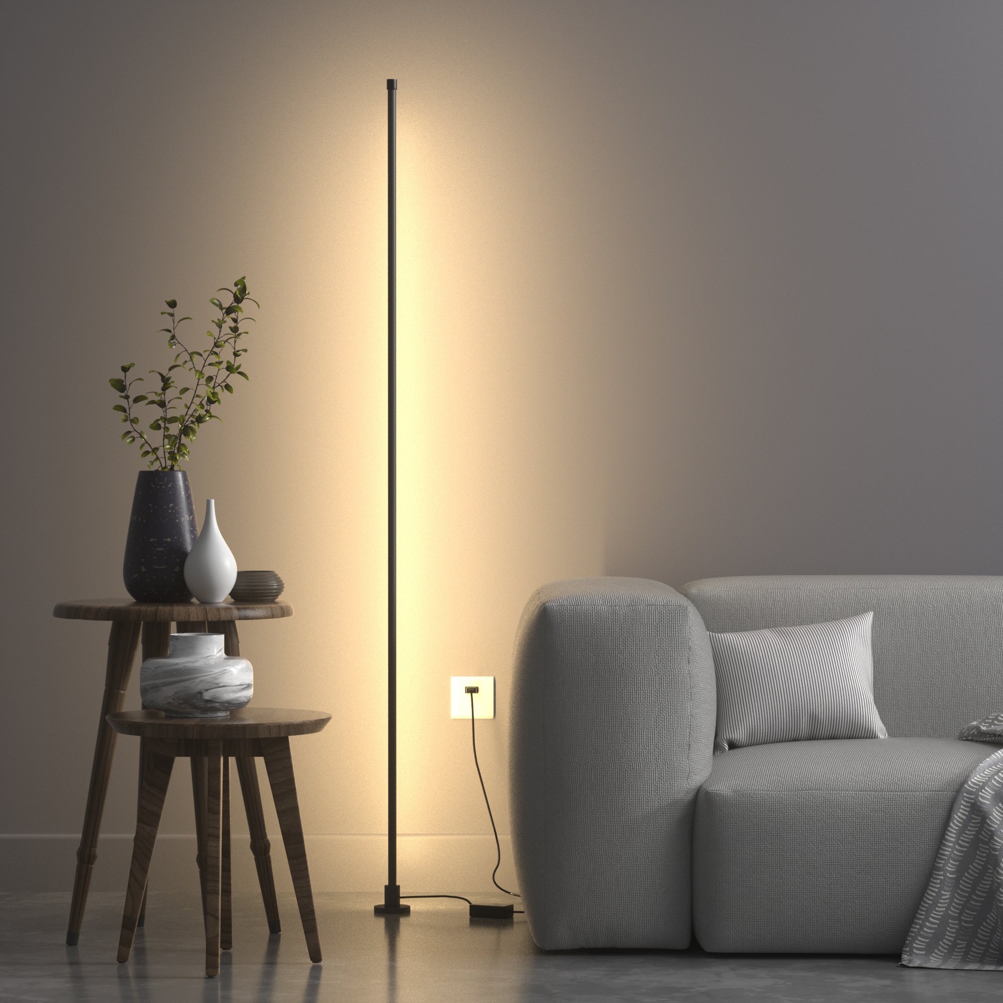 一支極簡設計的智慧落地氛圍燈，擺設在灰色沙發旁的角落，其光線投射於牆面，營造出溫暖且柔和的間接照明氛圍。
