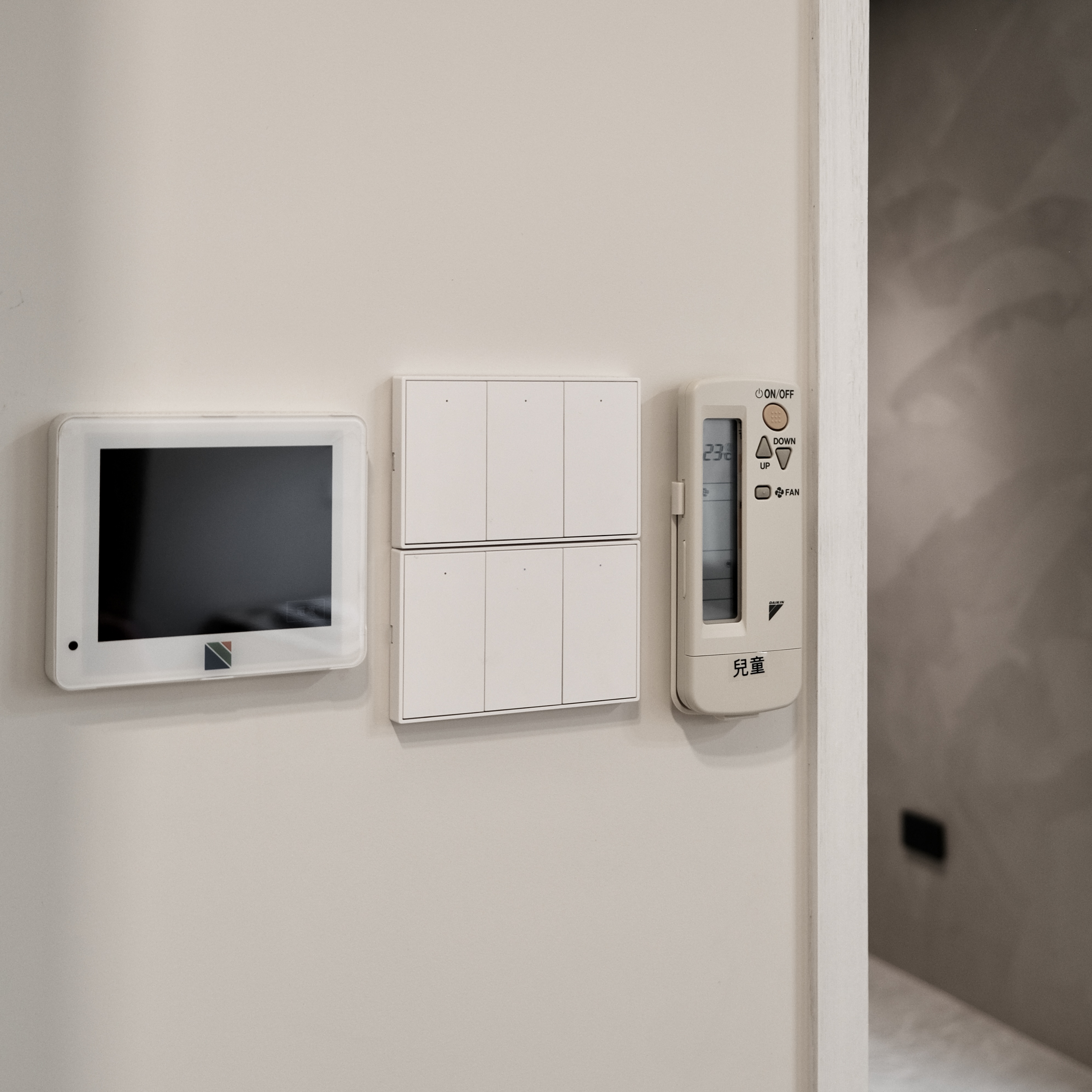 牆面上整合了多種控制器，包含一台中央空調面板、兩組 Zemismart K606 智慧開關以及一支空調遙控器。