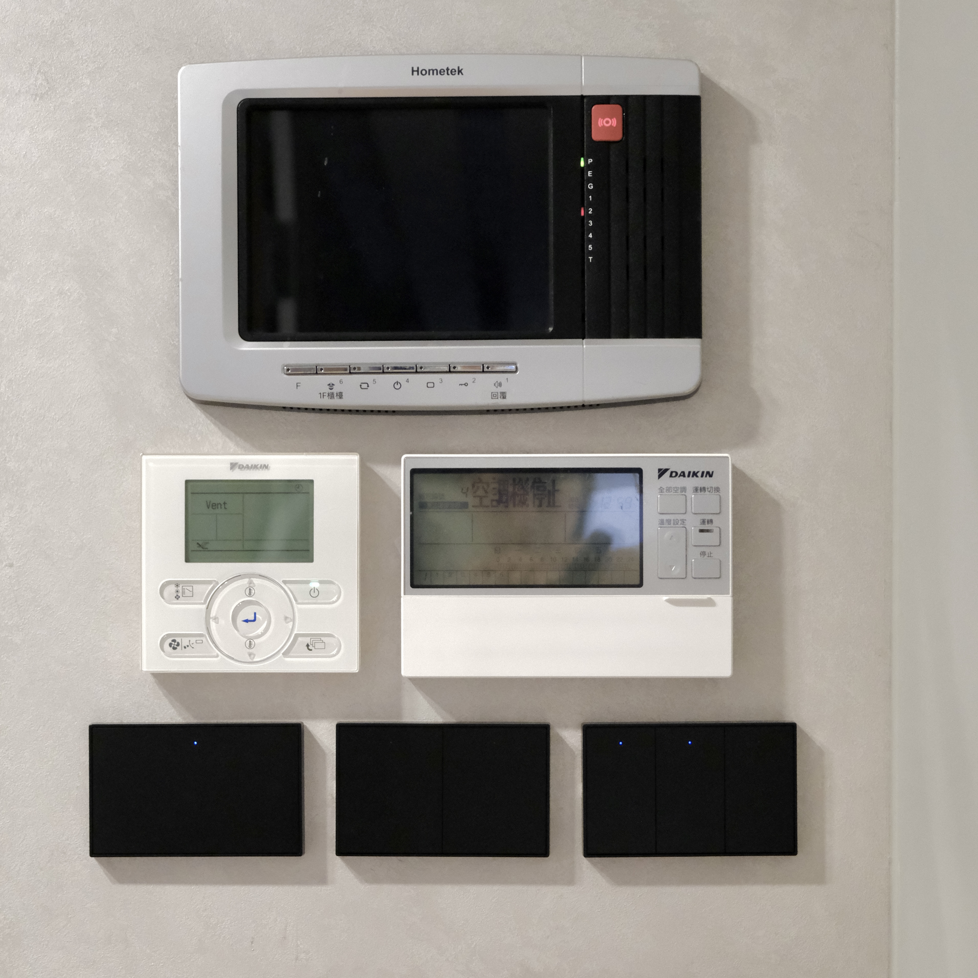 牆面上整合了多種智慧家庭控制器，包含了 Hometek 社區對講機、兩台 Daikin 空調面板，以及三組橫向排列的黑色 Zemismart K606 智慧開關。